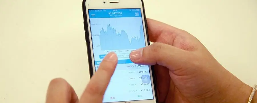 segurando celular na mao olhando gráfico de cotações
