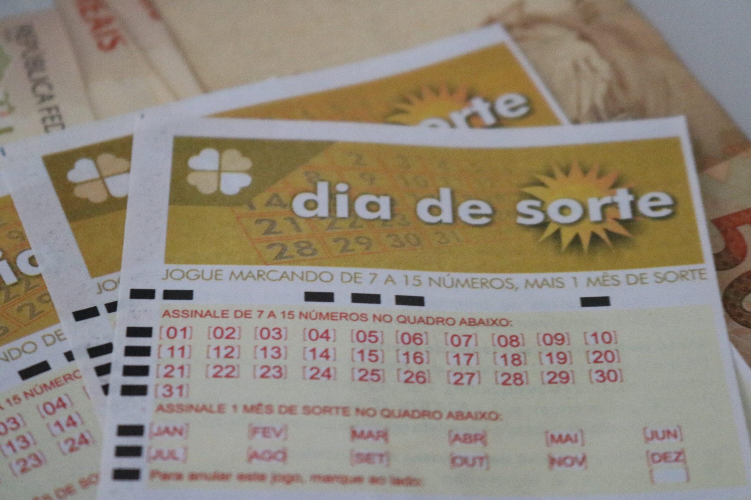 Dia de Sorte 383 - Volante do Dia de Sorte sobreposto em outros volantes e notas de dinheiro