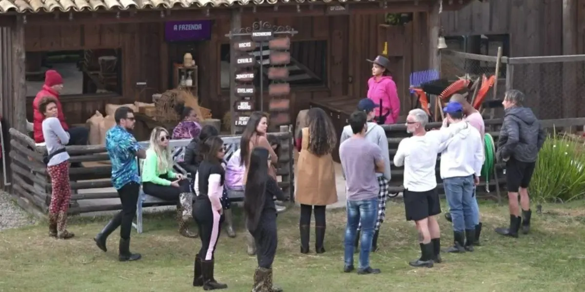 Jakelyne no gramado de A Fazenda com os peões em volta