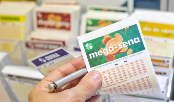 Resultado da Mega-Sena de ontem - a imagem mostra uma mão segurando um volante da Mega-sena e uma caneta