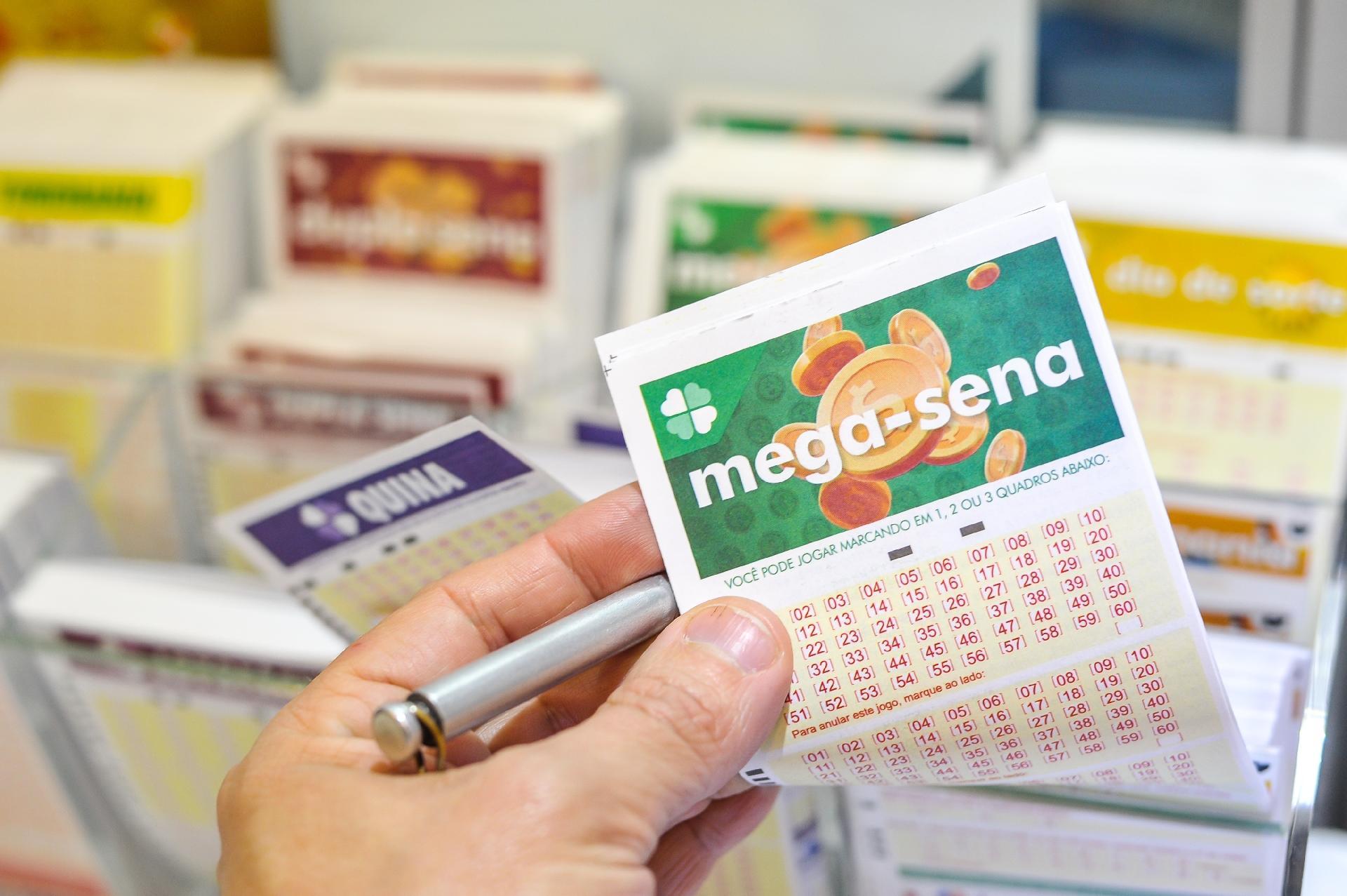 Resultado da Mega-Sena de ontem - a imagem mostra uma mão segurando um volante da Mega-sena e uma caneta