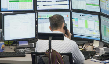 O que é Market Maker e como funciona? market maker sentado ao telefone em frente a várias telas de computador
