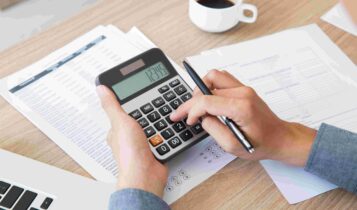 Pessoa com calculadora. Impostos federais, estaduais e municipais.