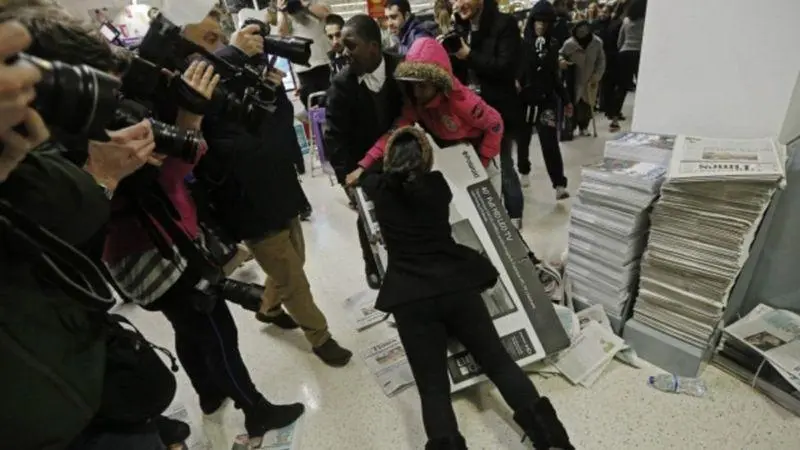 Clientes em loja disputando caixa do produto e pessoas gravando a cena.