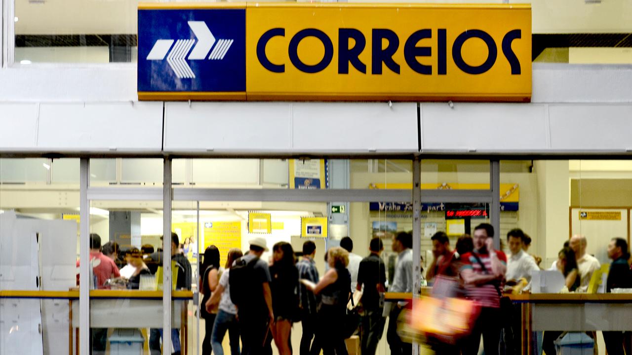 Foto mostra faixada dos Correios com pessoas na entrada
