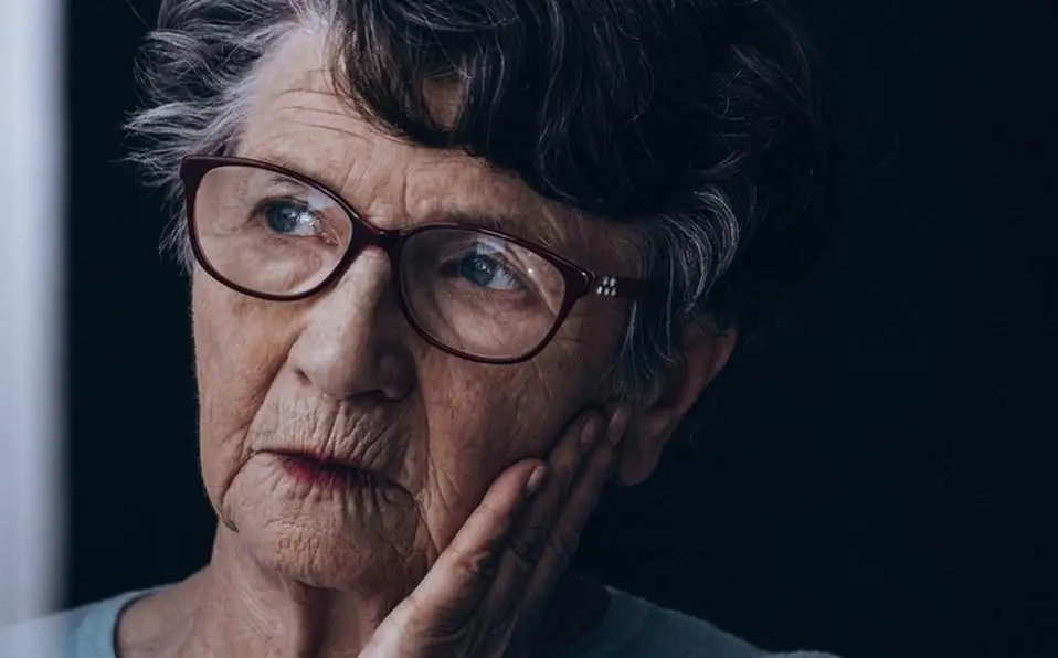 Foto mostra senhora idosa com mão no rosto