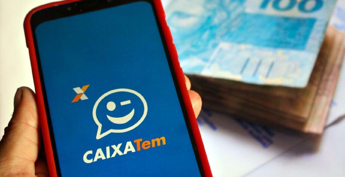 celular com logotipo do aplicativo Caixa Tem e cédulas de dinheiro ao fundo