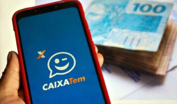 celular com logotipo do aplicativo Caixa Tem e cédulas de dinheiro ao fundo