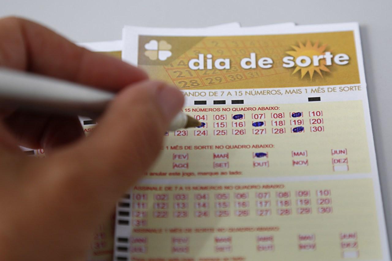 dia de sorte 376 - a imagem mostra uma mão segurando uma caneta e marcando números em um volante do Dia de Sorte