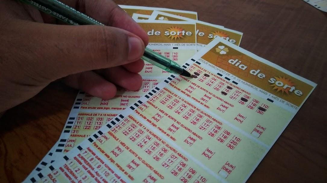 resultado do dia de sorte 404 - A imagem mostra uma mão segurando uma caneta e marcando números no volante do Dia de Sorte