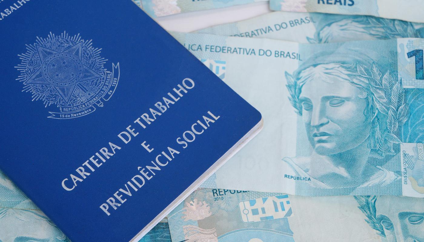 Foto de notas de 100 do pagamento do 13º e uma carteira de trabalho