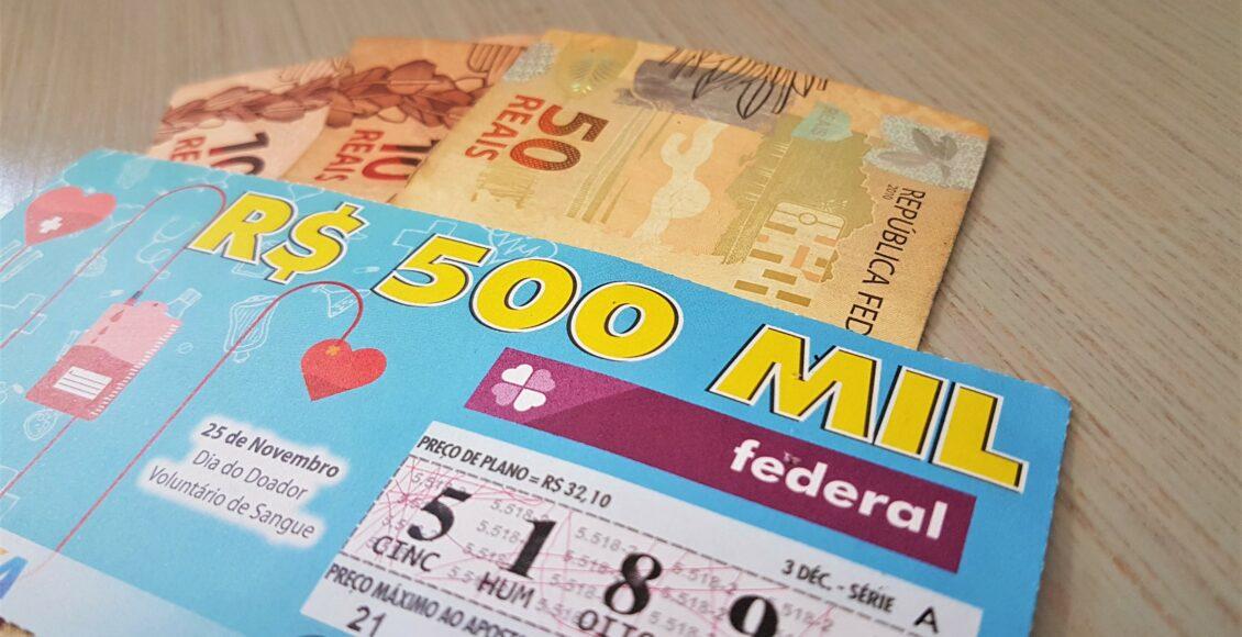 resultado da loteria federal 5518 - A imagem mostra um bilhete da loteria federal sob uma nota de cinquenta reais e duas de dez reais