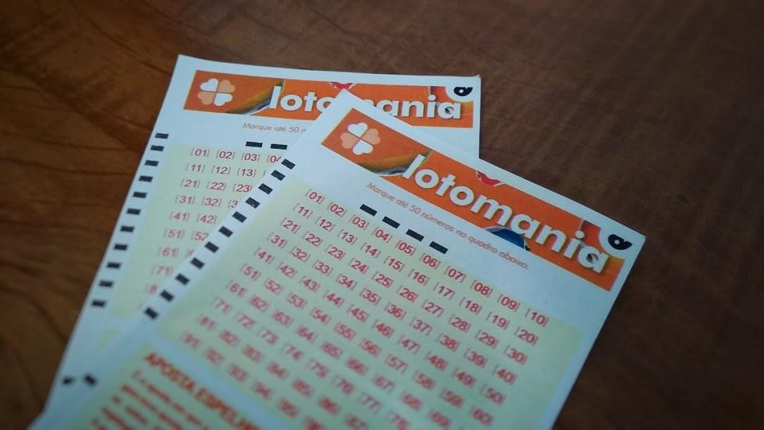 resultado da lotomania 2130 - na imagem dois bilhetes da lotomania embranco sob uma mesa