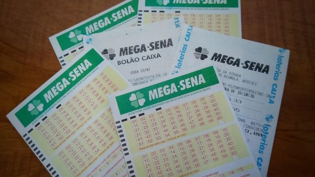 A imagem mostra diversos volantes e apostas da Mega Sena espalhados