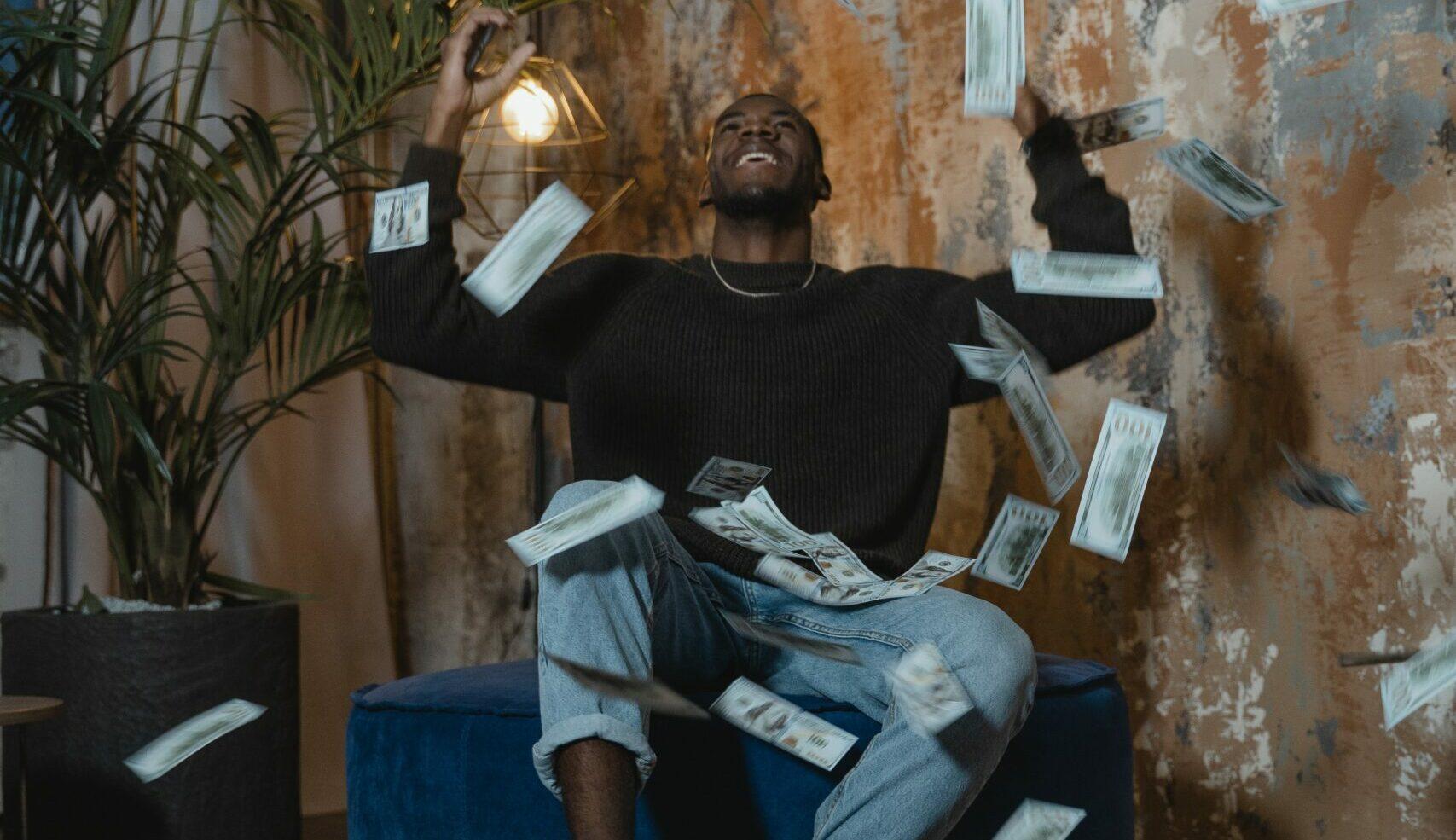 A imagem mostra um homem feliz em meio a chuva de dinheiro