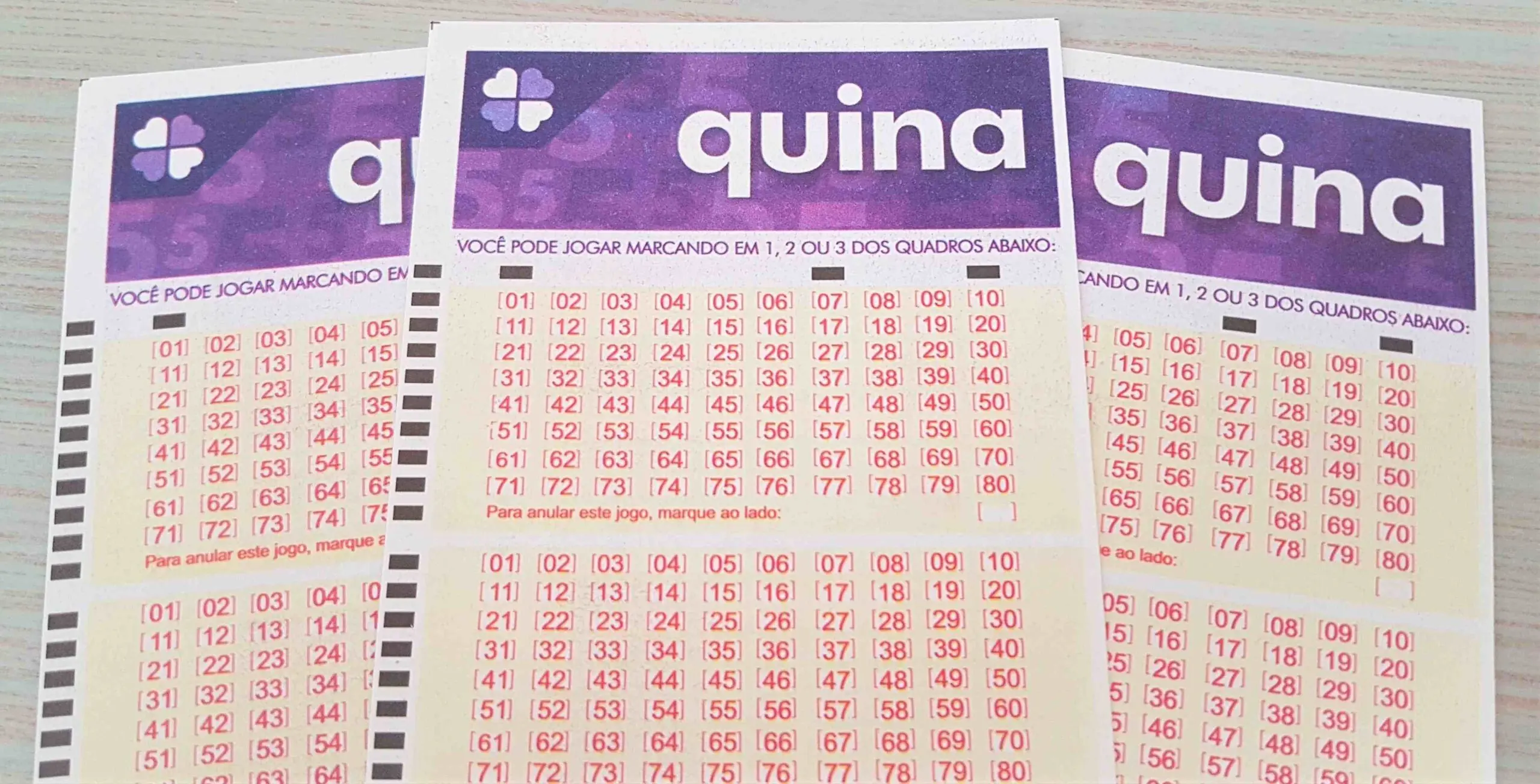 resultado da quina 5430 - três bilhetes da quina dispostos sobre uma mesa
