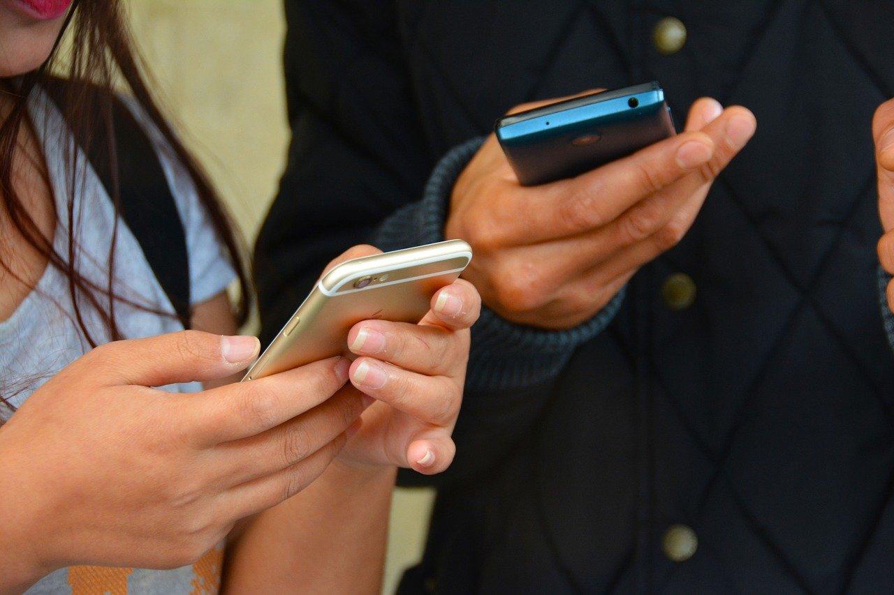 Duas pessoas usando celular. Pix Cobrança.