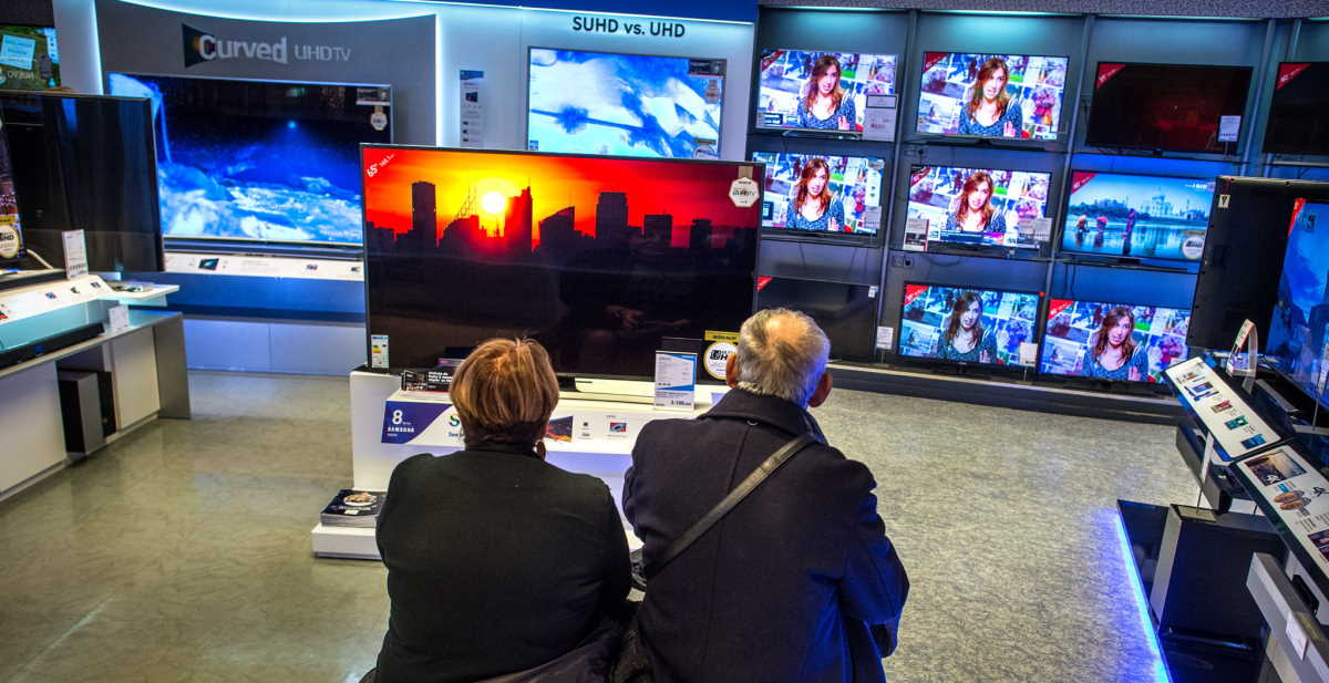 Casal sentado na loja vendo TV promoção no Black Friday