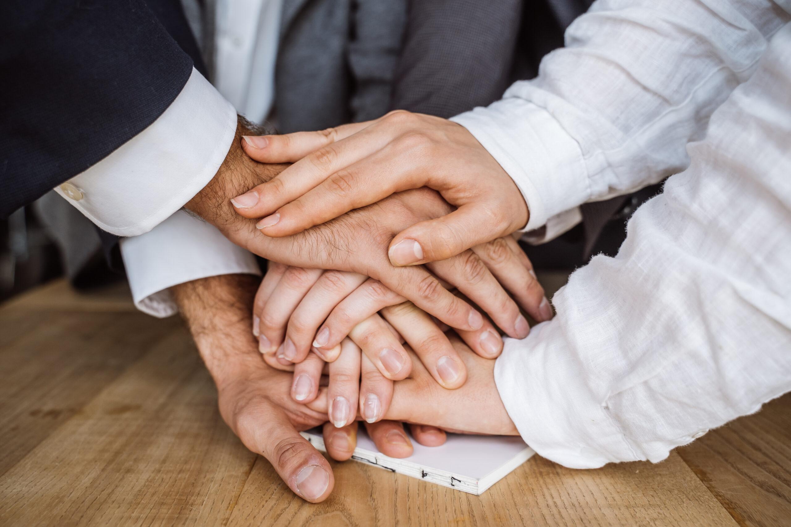 Diversas mãos unidas sobre outras para comemorar férias coletivas
