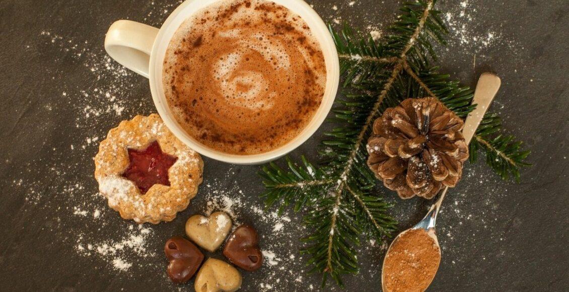 Imagem mostra xícara com chocolate quente e enfeites de Natal ao redor