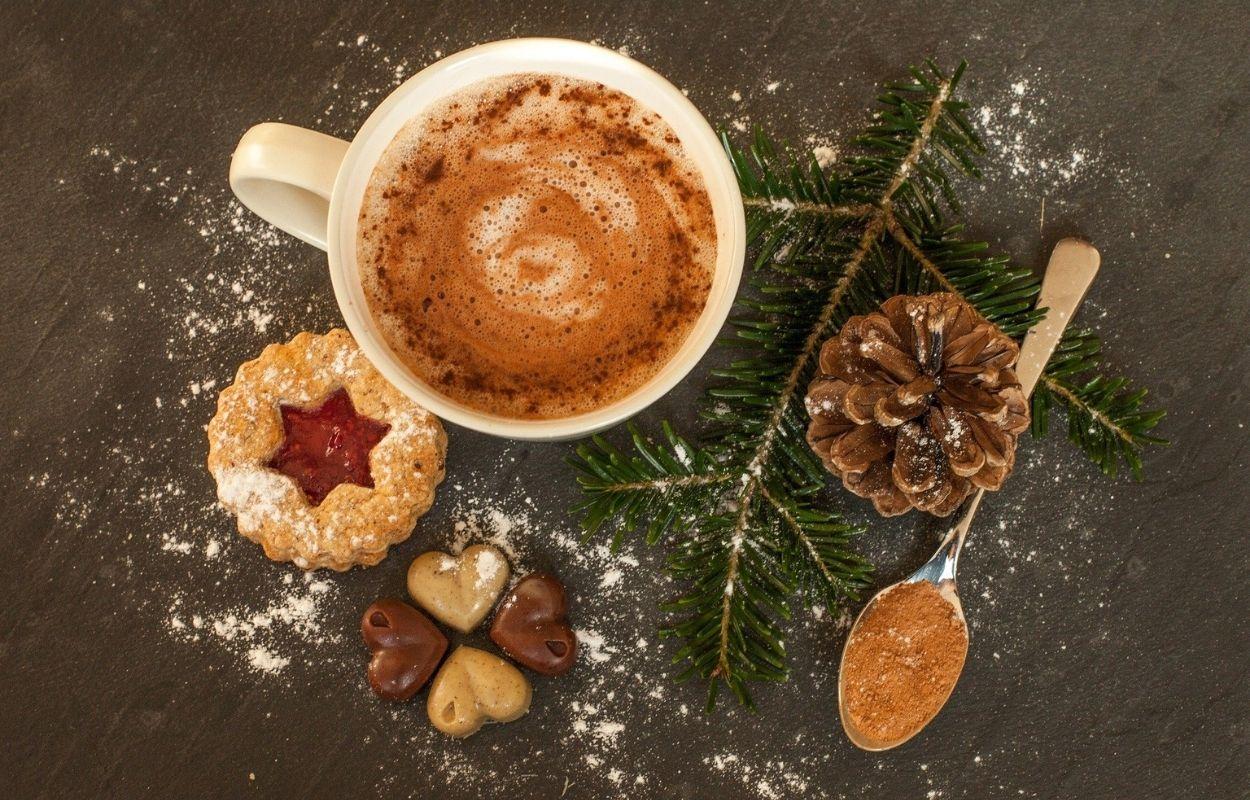 Imagem mostra xícara com chocolate quente e enfeites de Natal ao redor