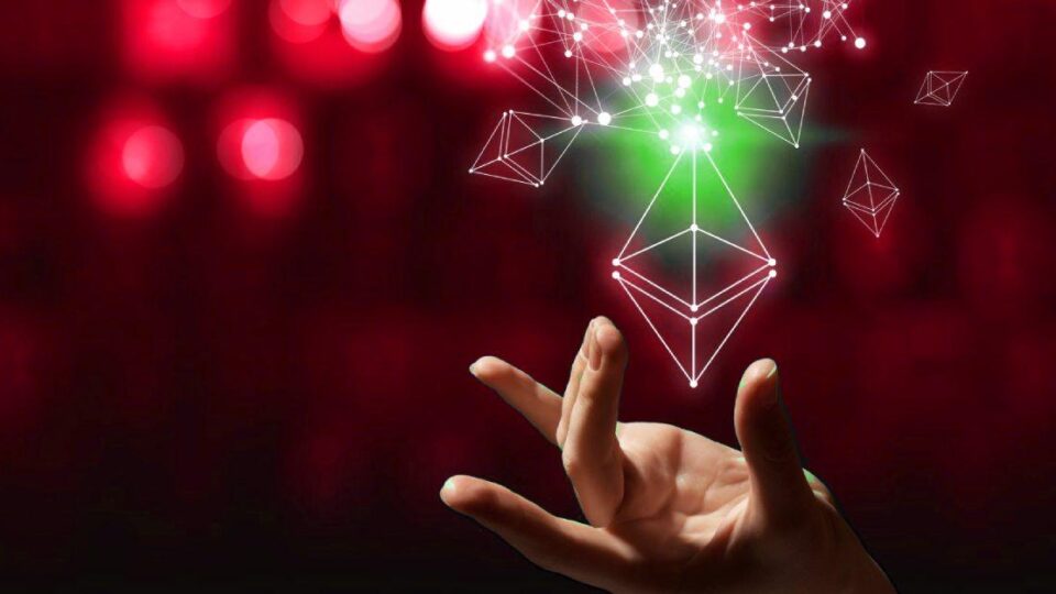 Mão segurando logotipo da ETH 2.0, nova rede Ethereum, em fundo vermelho