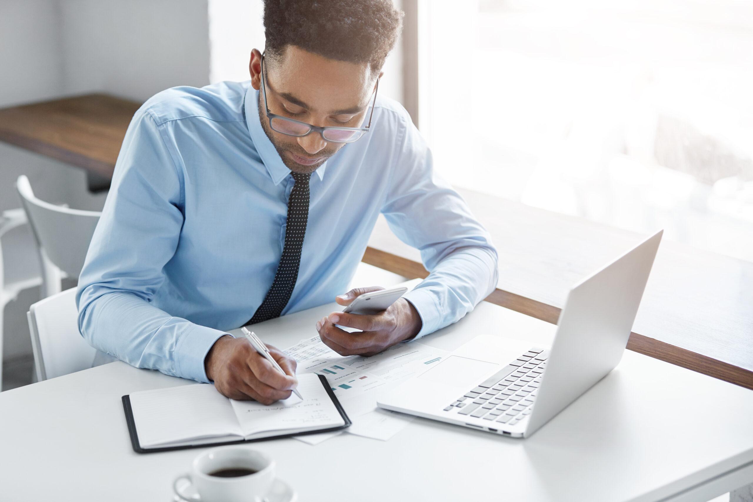 Homem fazendo anotações em frente a notebook