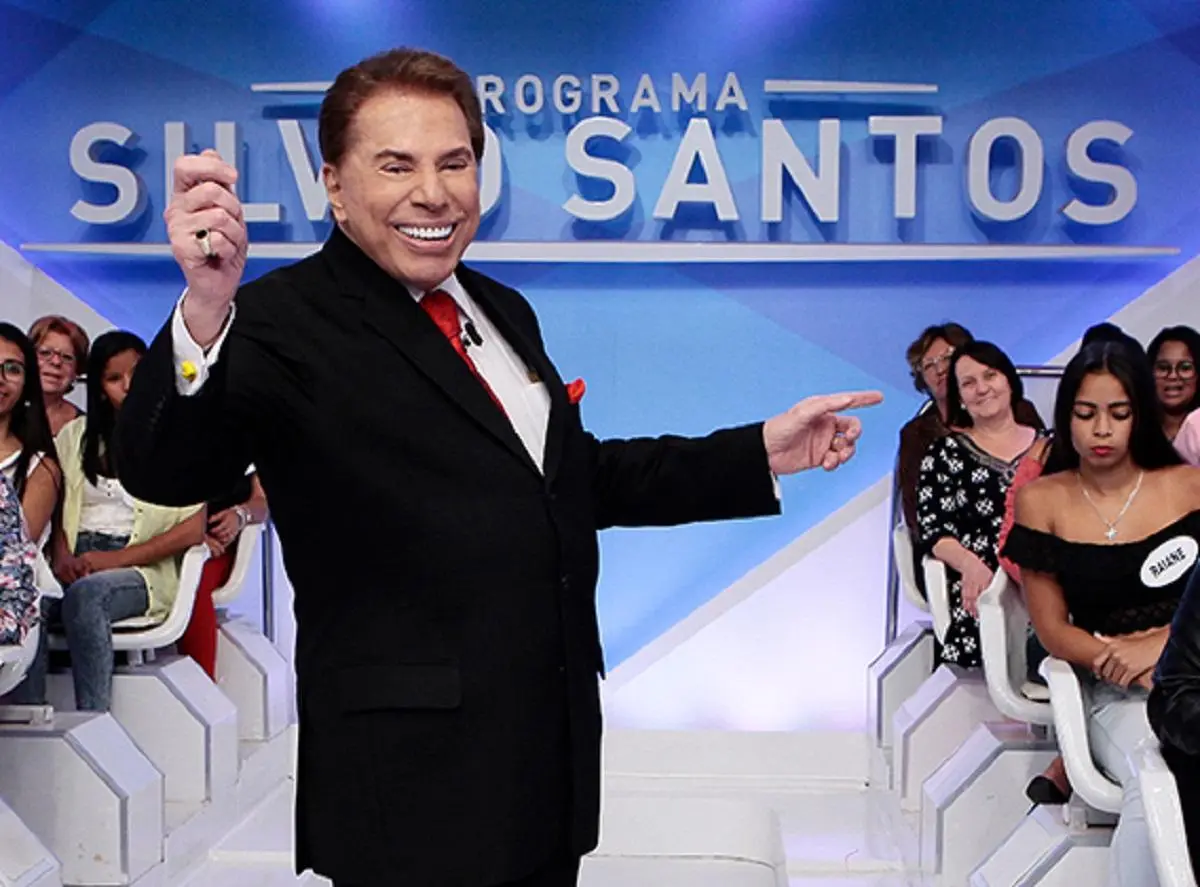 A imagem mostra Silvio Santos apresentando seu programa