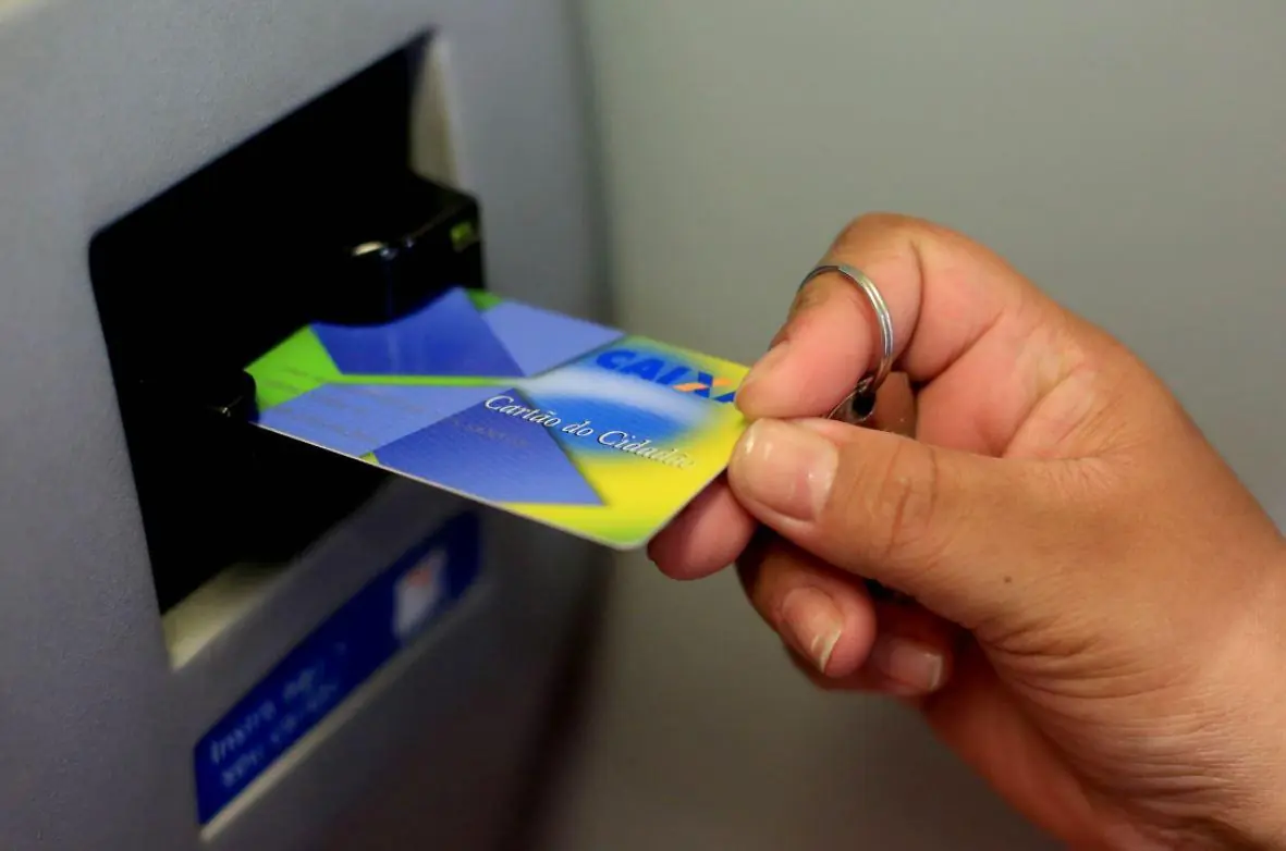 Foto mostra pessoa inserindo o Cartão Cidadão em caixa eletrônico