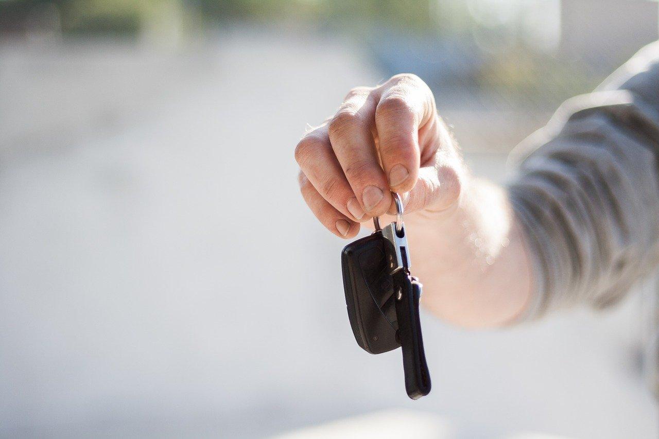 Foto aproximada mostra mãos segurando chave de carro.