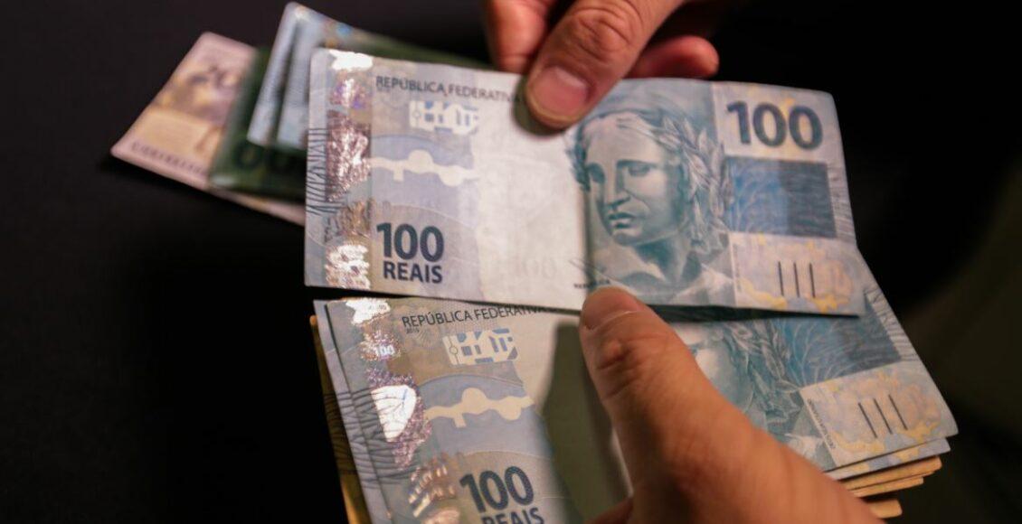 matéria fala de quem tem direito à pensão por morte do segurado do INSSFoto mostra homem contando notas de 100 reais.