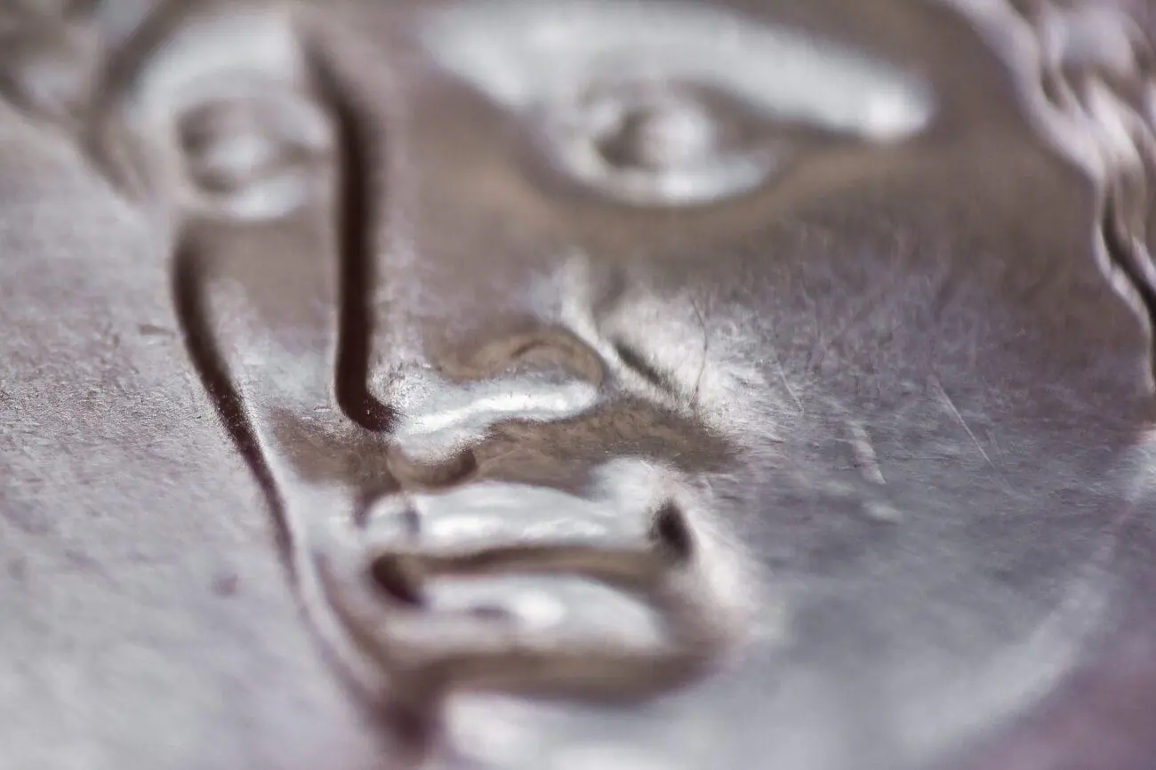 Foto aproximada mostra rosto em moeda de 1 real. em rendimento da poupança 2021