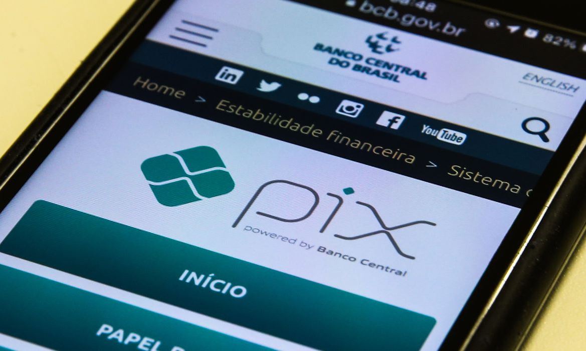 Foto mostra celular aberto em página informativa do Banco Central sobre o Pix movimentar contas salário.