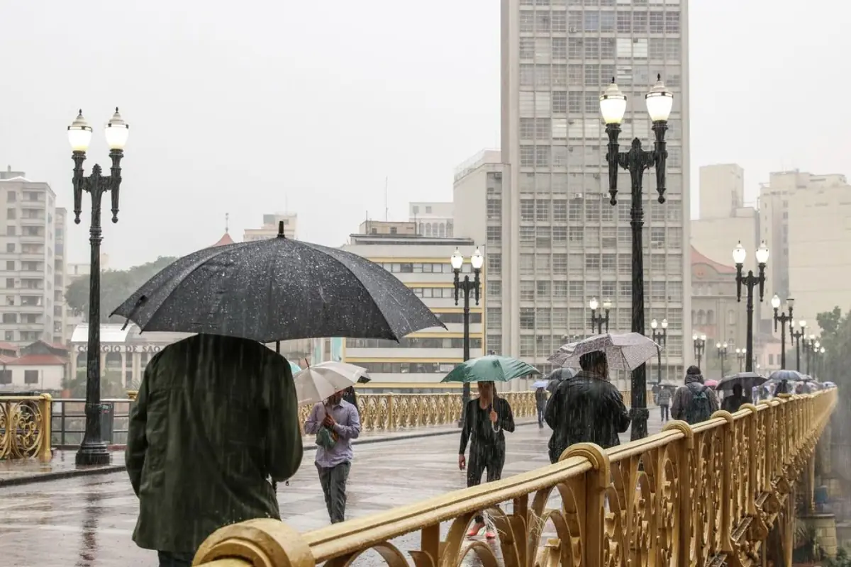 Imagem capturada no viaduto Santa Ifigênia,em São Paulo, mostra pessoas com guarda-chuva. Chuva em São Paulo