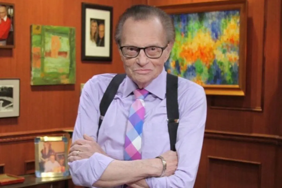 Imagem posada do jornalista Larry King. Ele está de braços cruzados.