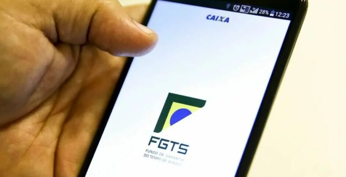 Imagem mostra mão masculina segurando celular com tela do FGTS