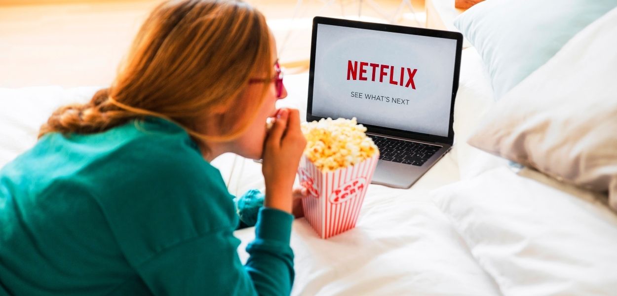 Mulher comendo pipoca e assistindo o Top 10 Netflix