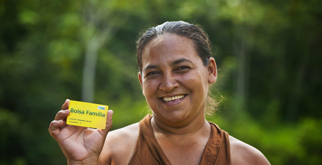 Mulher segurando cartão do Bolsa Família