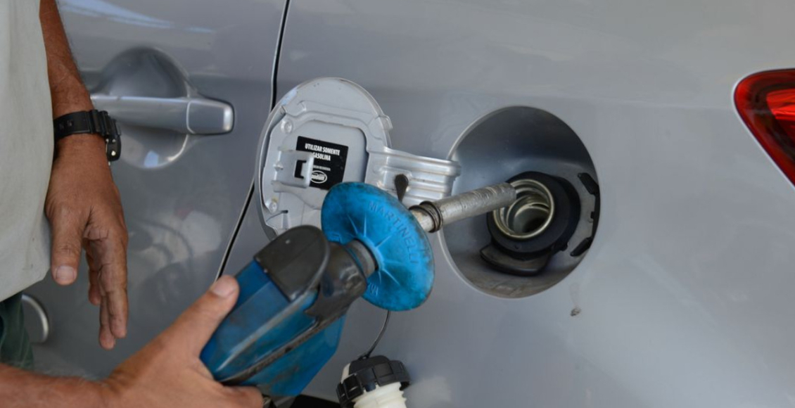 Foto mostra um profissional abastecendo o tanque de um carro com gasolina.