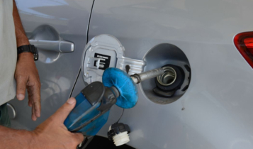 Foto mostra um profissional abastecendo o tanque de um carro com gasolina.