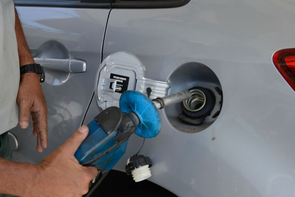 Foto mostra um profissional abastecendo o tanque de um carro com gasolina.