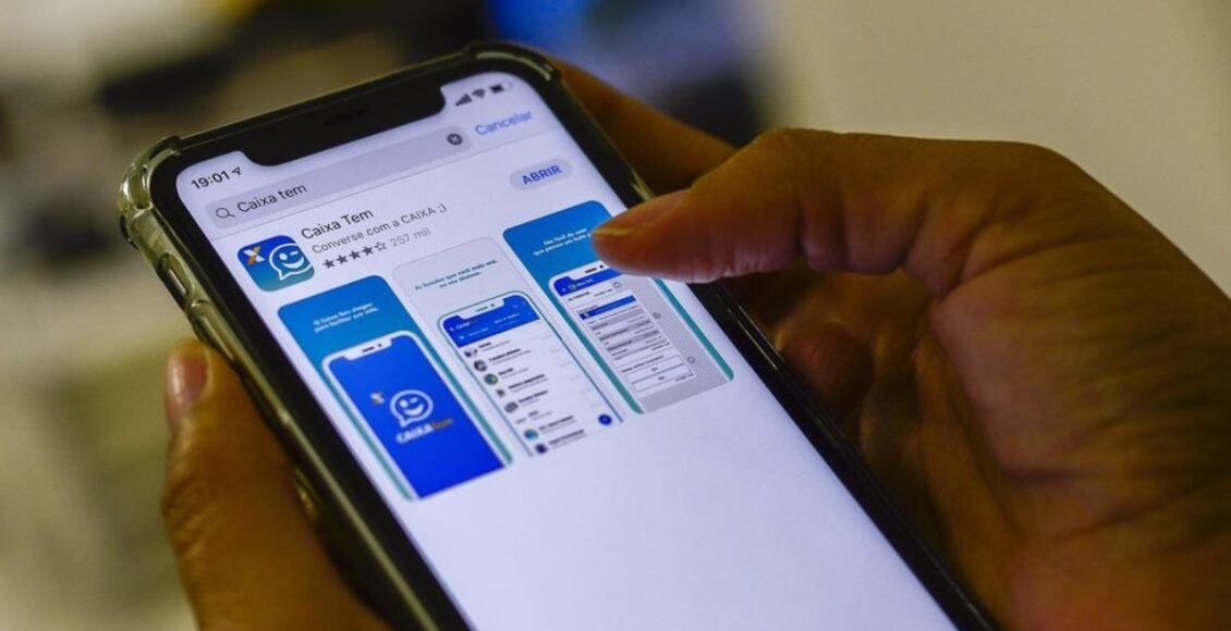 Na foto, mãos seguram um celular que, na tela, exibe o aplicativo Caixa Tem, pelo qual é possível ver se foi recebido o benefício do Bolsa Família