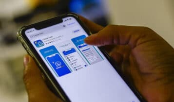 Na foto, mãos seguram um celular que, na tela, exibe o aplicativo Caixa Tem, pelo qual é possível ver se foi recebido o benefício do Bolsa Família
