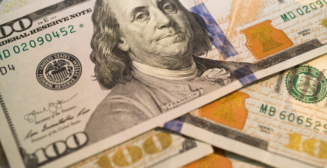 Várias notas de dólar com foco na que está em primeiro plano