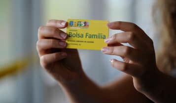mãos segurando um cartão do Bolsa Família