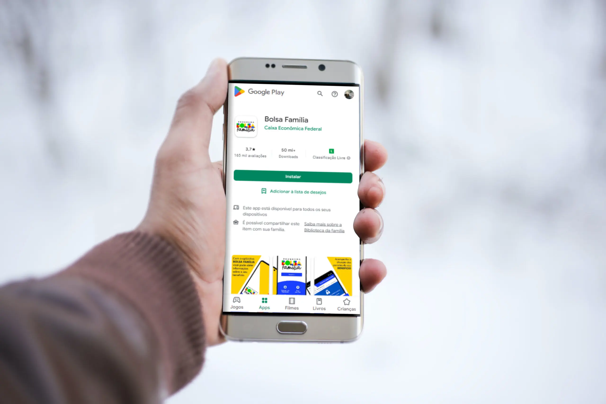 Mão segurando o celular mostrando o aplicativo do Bolsa Família
